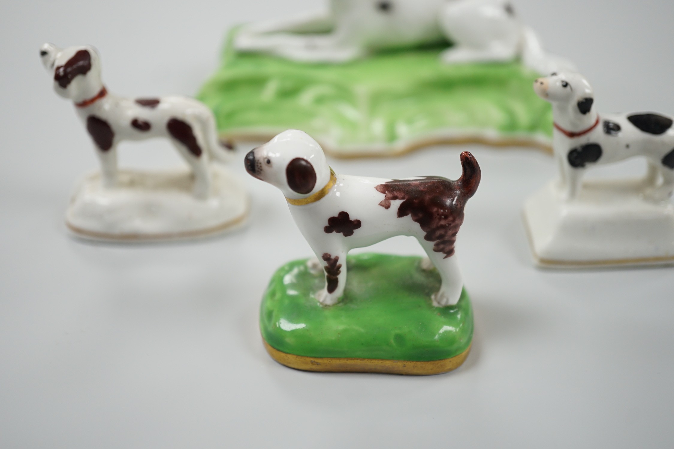 Three toy Staffordshire models of standing terriers; two with brown spots and the other black spots, together with a small Staffordshire model of a recumbent black and white setter on modelled base. c.1830-50, Largest 13